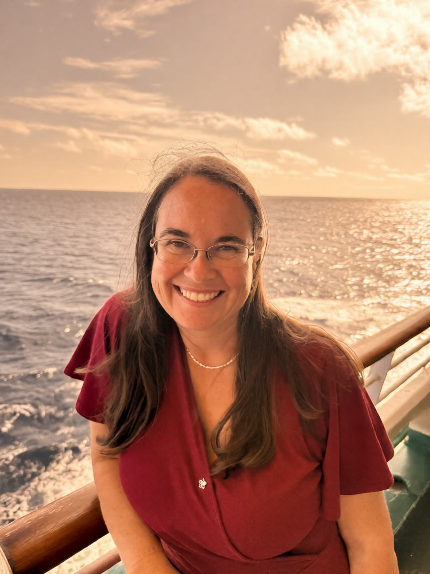Jonita Colling-Holland smiling beside the ocean in warm sunset light